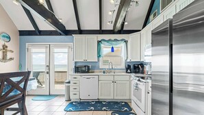 Una cocina con armarios blancos, un refrigerador de acero inoxidable y una alfombra azul y blanca en el suelo.