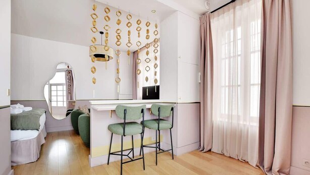 A modern kitchen with a central island, bar stools, and pendant lights. - A Stunning Studio-Loft in Place Vendôme - Louvre (Paris)