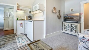 A compact living space with a kitchenette, a flat-screen TV, and a decorative cabinet. - Beautiful inn, Lighthouse Landing. #5 Beach Rose (Ogunquit)
