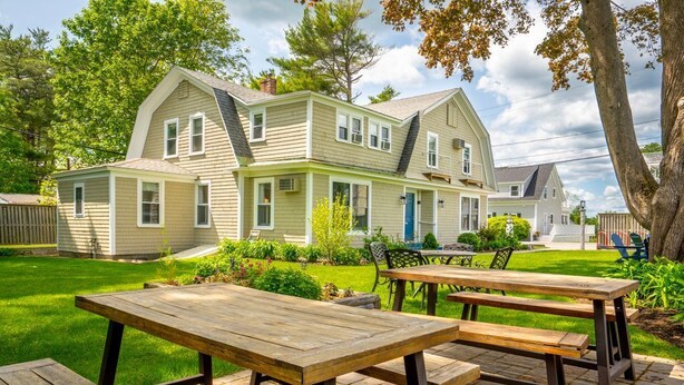 A two-story house with a front porch, a lawn, and a picnic table set up in the yard. - Beautiful inn, Lighthouse Landing. #5 Beach Rose (Ogunquit)