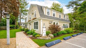 A two-story house with a sloped roof, a front porch, and a small garden area with a stone lantern. - Beautiful inn, Lighthouse Landing. #2 Sea Cliffs (Ogunquit)
