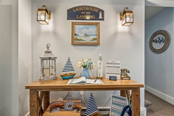 A reception desk with a sign reading "Lighthouse Landing," a framed painting of a lighthouse, and a vintage telephone. - Beautiful inn, Lighthouse Landing. #2 Sea Cliffs (Ogunquit)