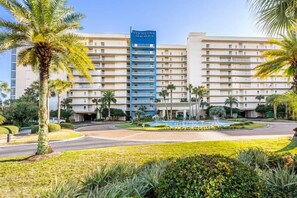 A hotel with multiple floors, a central fountain, and palm trees.