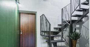 Un intérieur moderne avec un escalier, une porte en bois et un mur vert.