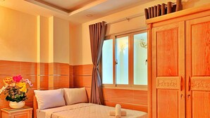 A hotel room with a bed, a nightstand with a vase of flowers, a wardrobe, and a window with curtains. - S79 Hotel 868 Binh Tan (Ho Chi Minh City)