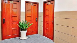 Three wooden doors with numbers 501, 502, and 504, and a potted plant on a marble floor. - S79 Hotel 868 Binh Tan (Ho Chi Minh City)