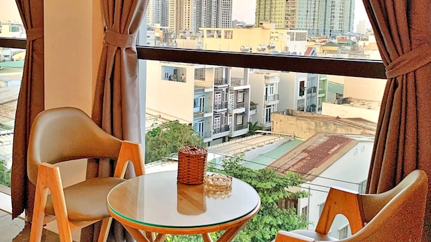 A balcony with two chairs and a small table, overlooking a cityscape with high-rise buildings. - S79 Hotel 868 Binh Tan (Ho Chi Minh City)