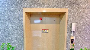 An elevator with emergency exit signs, a phone, and two potted plants. - S79 Hotel 868 Binh Tan (Ho Chi Minh City)