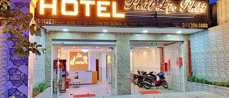 The exterior of 868 Hotel with a neon sign, reception area, and parked motorcycles.