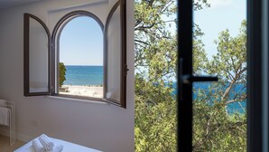 Una stanza con un'ampia finestra ad arco che si affaccia su una spiaggia e il mare.
