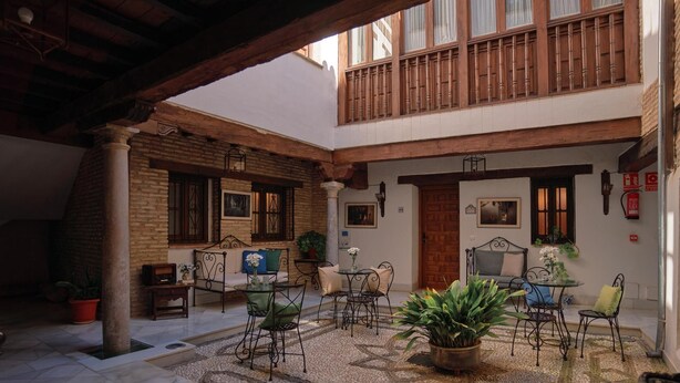 A courtyard with a seating area, a wooden balcony, and a door. - Charminghomesgranada Aljibe Antiguo Apartment (Granada)