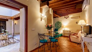 A cozy living room with a dining area, a TV, and a decorative wall piece. - Charminghomesgranada Aljibe Granadino Apartament (Granada)