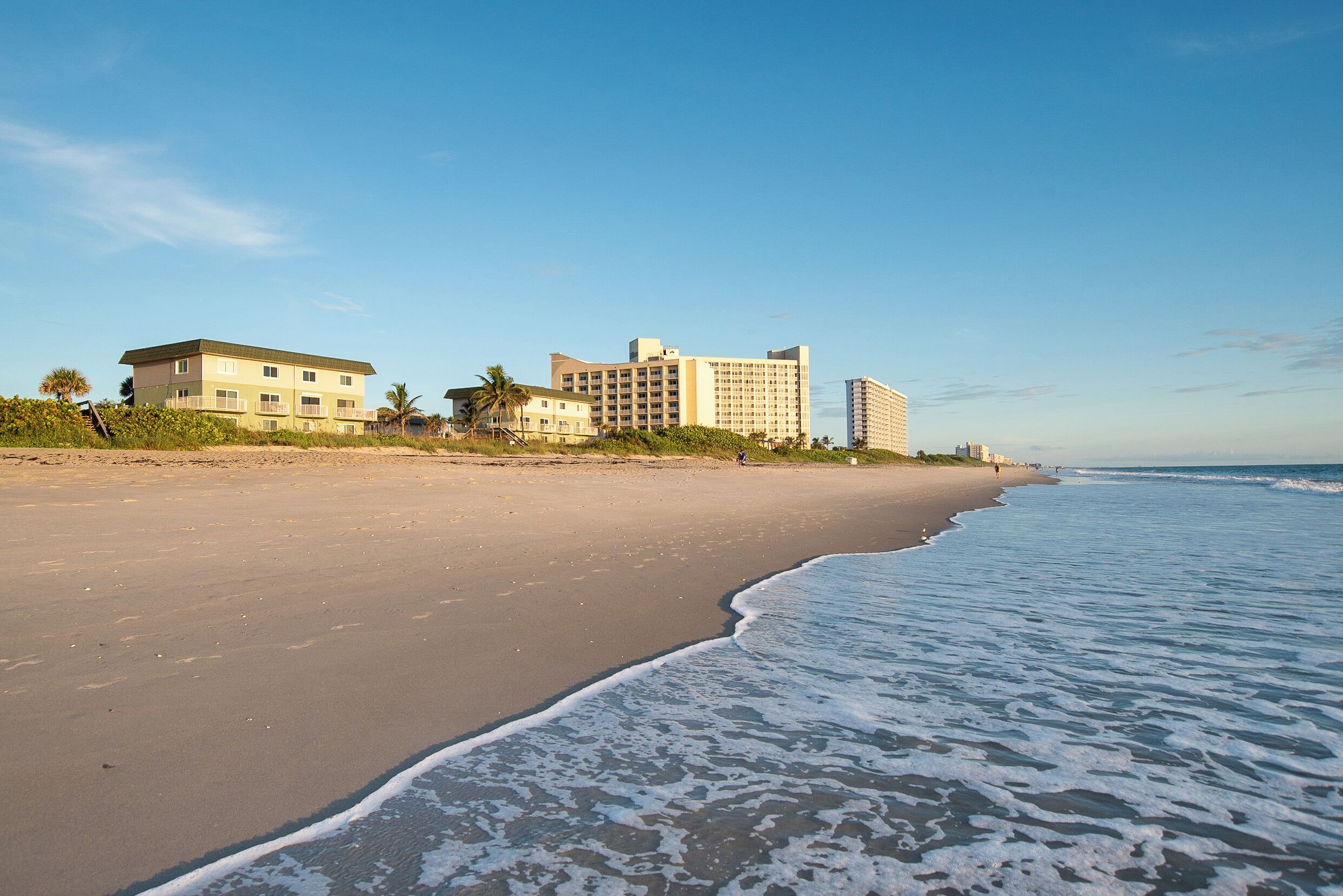 Ein Strand mit einem Hotel und Hochhäusern im Hintergrund.