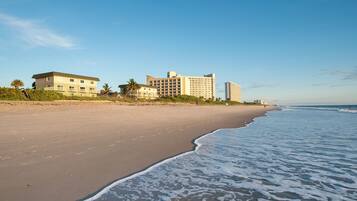 Ein Strand mit einem Hotel und Hochhäusern im Hintergrund.