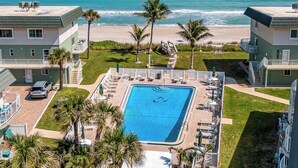 A pool with a view of the ocean, surrounded by palm trees and a beach. - Balcony & A Patio, Private Beach Access, Heated Pool (Indialantic)