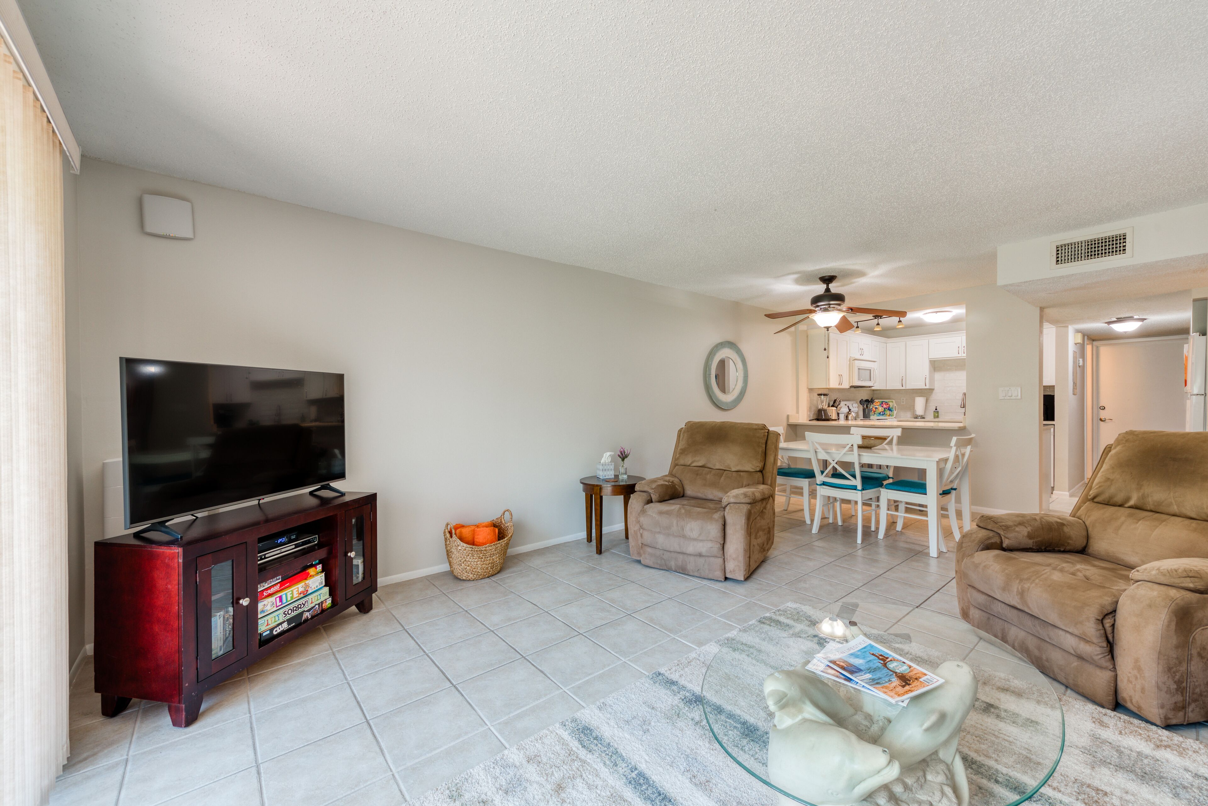 A living room with a flat-screen TV, a glass coffee table, and a sofa.