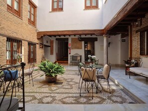 A courtyard with a tiled floor, outdoor seating, and a central plant. - Charminghomesgranada Rio Genil Apartament (Granada)