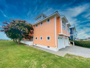 A two-story residential building with a brick facade, a garage, and a well-maintained lawn.