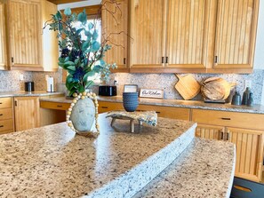 Una cocina con armarios de madera, encimera de granito, un jarrón decorativo y un letrero que dice 'Our Kitchen'.