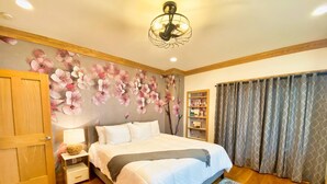 Une chambre à coucher avec un lit, un plancher en bois, un papier peint à motifs floraux, une bibliothèque et une fenêtre avec des rideaux.
