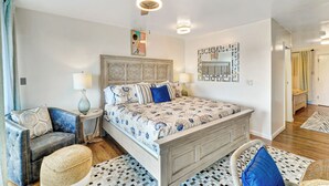 Ein Schlafzimmer mit einem Bett, zwei Nachttischen, einem Sessel, einem Deckenventilator und einem an der Wand befestigten Spiegel.