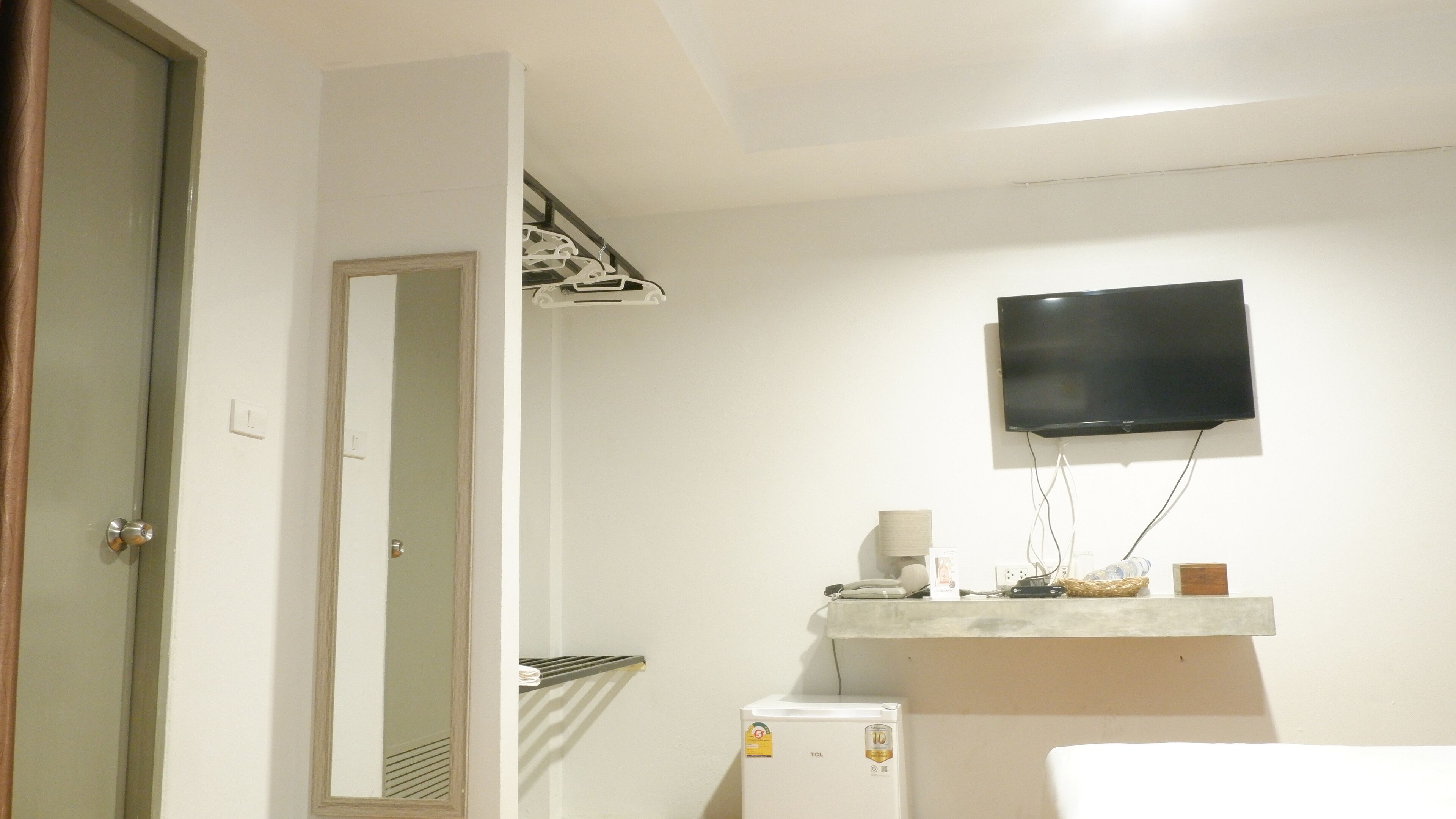 A bathroom with a white sink, a mirror, a towel rack, a toilet, and a television mounted on the wall.