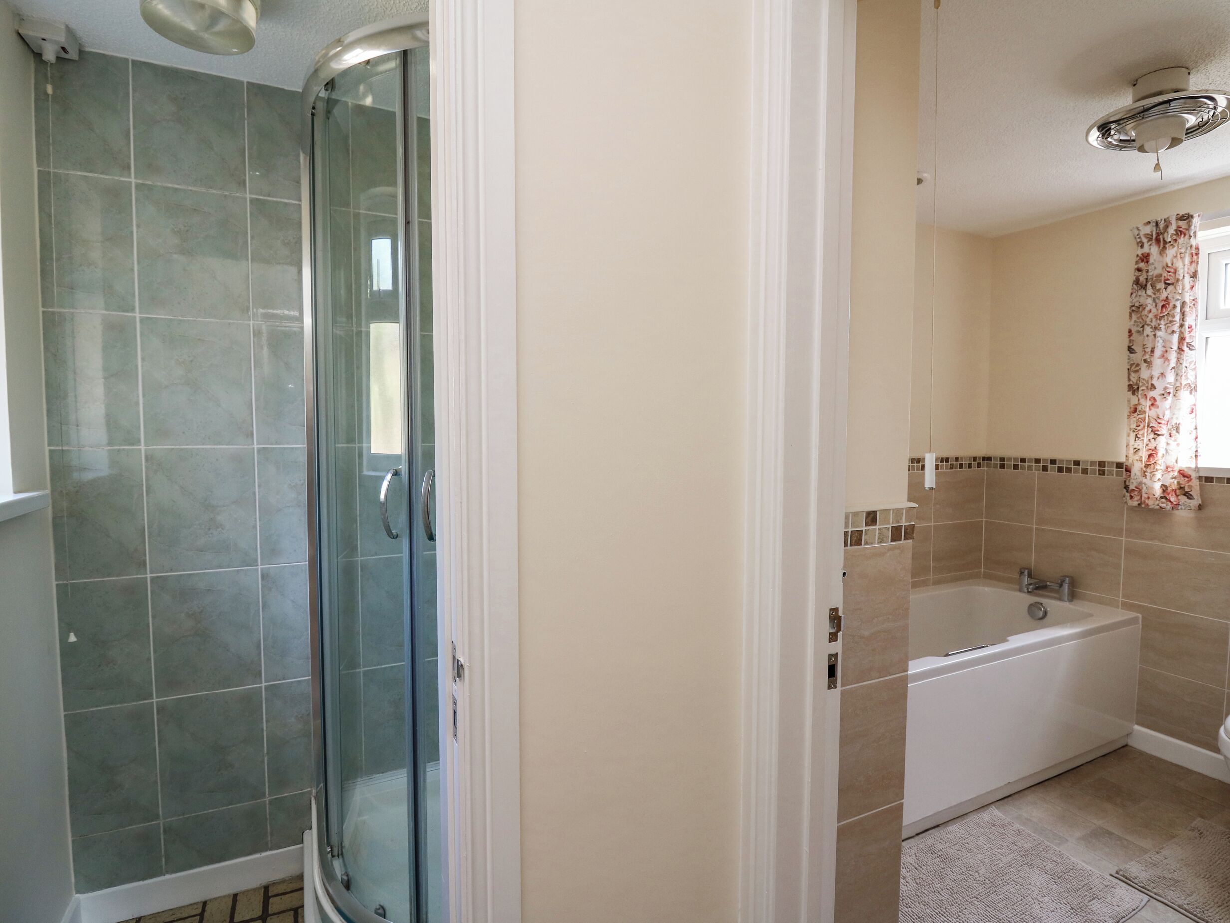 Un baño con ducha de vidrio, bañera y retrete.