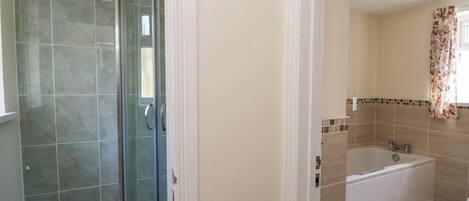 Un baño con ducha de vidrio, bañera y retrete.