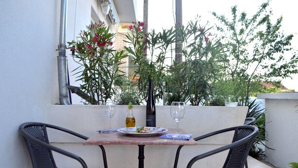 Un espace extérieur aménagé pour prendre les repas, avec deux chaises, une table et une bouteille de vin.