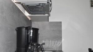 Une cuisine équipée d’une machine à café, d’un évier et d’un crédence en acier inoxydable.