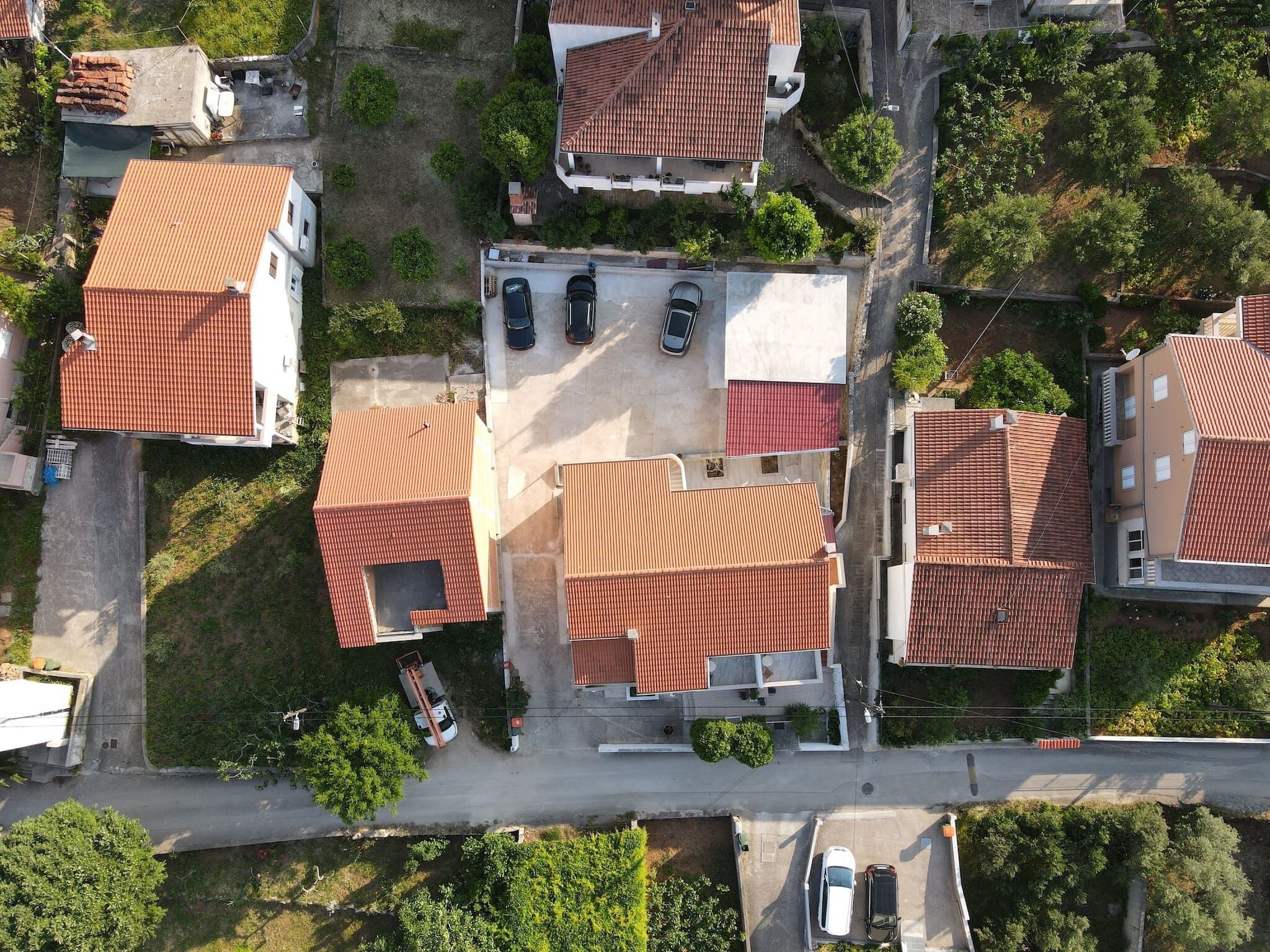 An aerial view of a residential area with multiple houses, each featuring red-tiled roofs and a mix of single and two-story structures.