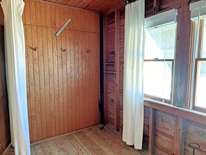 Une pièce aux murs en bois, une fenêtre avec des rideaux et une porte.