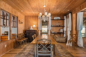 Une salle à manger en bois avec une grande table, des chaises et un lustre.