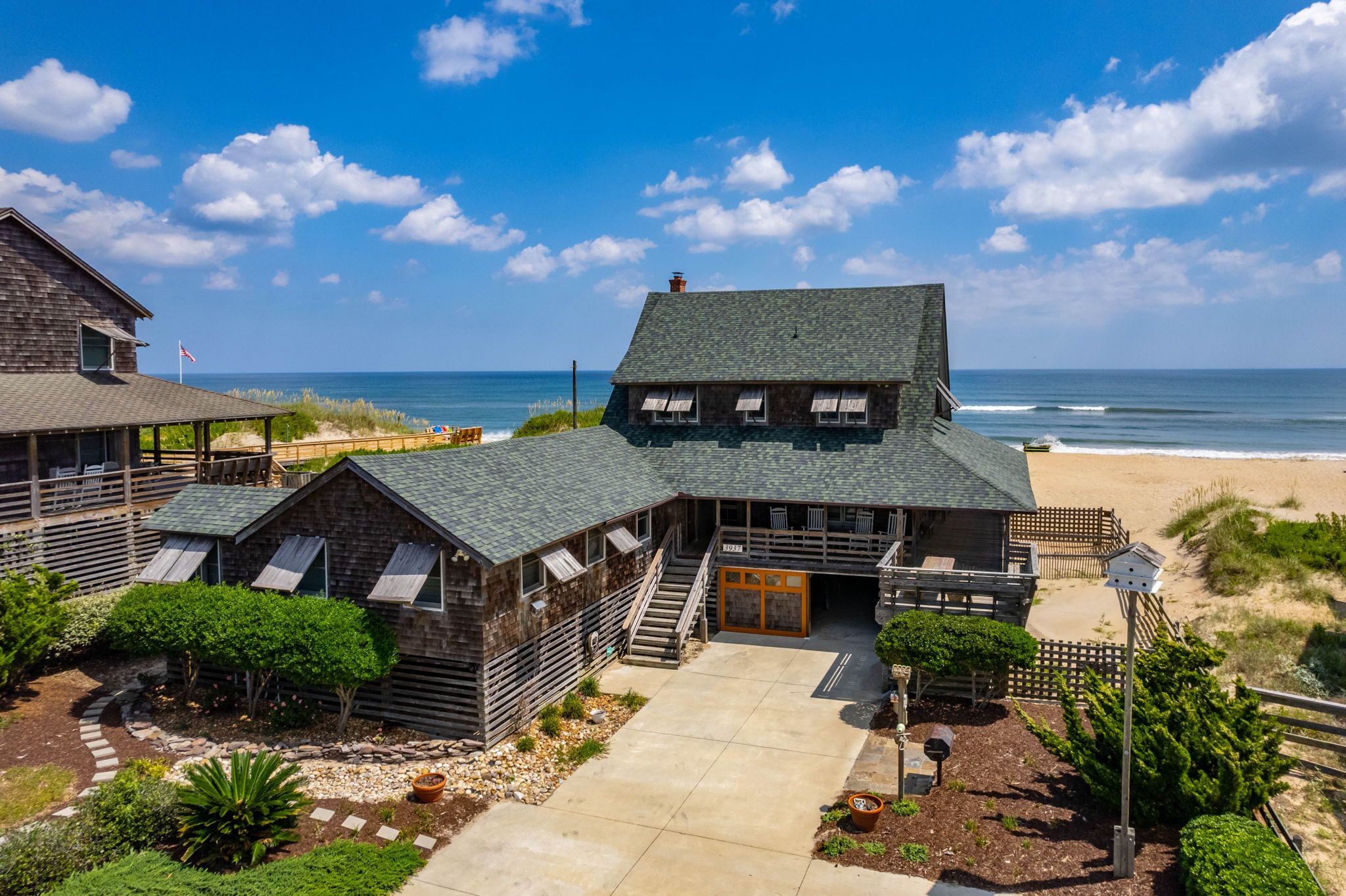 A coastal building with a stone facade, wooden deck, and a view of the ocean.