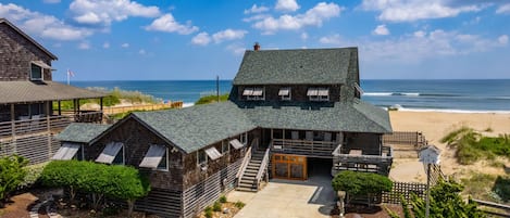 Una propiedad costera con una edificación principal, una terraza cubierta y vista al mar.