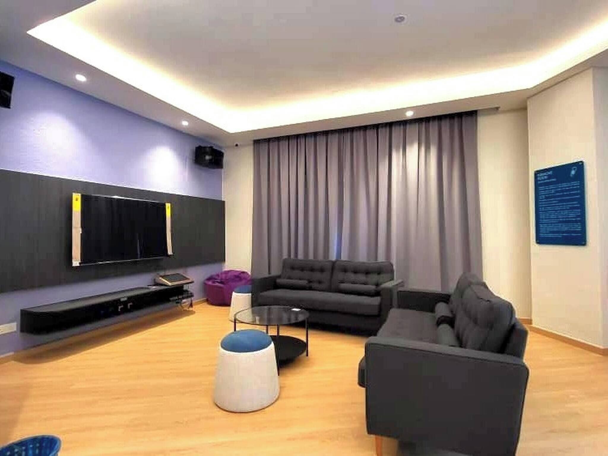 A modern living room with a flat-screen TV, two sofas, a coffee table, and a ceiling light.
