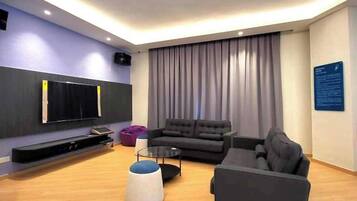 A modern living room with a flat-screen TV, two sofas, a coffee table, and a ceiling light.