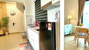Een moderne keuken met een koelkast, fornuis en spoelbak. Er is een eethoek met een tafel en stoelen.