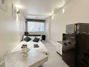 Una camera da letto compatta con un letto, un comodino e un frigorifero U-MAX.