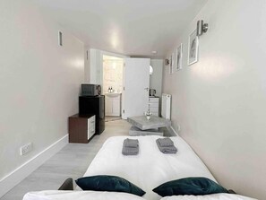 Camera d'albergo compatta con un letto, una piccola scrivania con un forno a microonde, un lavandino e un termosifone.