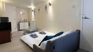 A modern bedroom with a bed, bedside tables, a dresser, and a television.