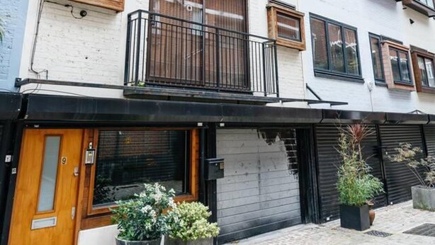 A multi-story building with a white facade, wooden balconies, and a black storefront.
