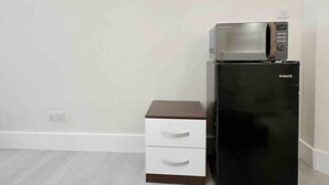 A black refrigerator with a U-MAX logo, a microwave on top, and a white cabinet with two drawers.