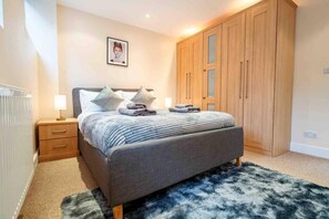 Quarto com cama, mesas de cabeceira, guarda-roupa e radiador.