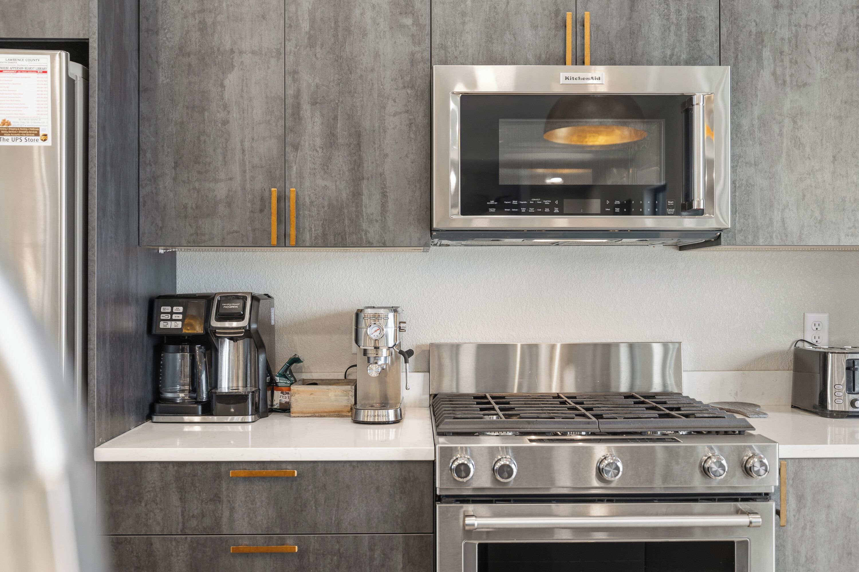 Eine Küche mit Edelstahl-Mikrowelle, Kaffeemaschine, Toaster, Herd und Backofen.