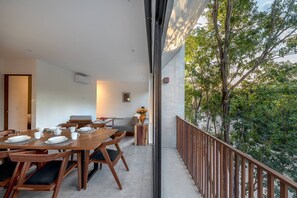 A dining area with a wooden table set for four, a sofa, and a small side table with a vase. - Unbeatable Located 2 Br Apt With Amazing Natural Lig (Tulum)