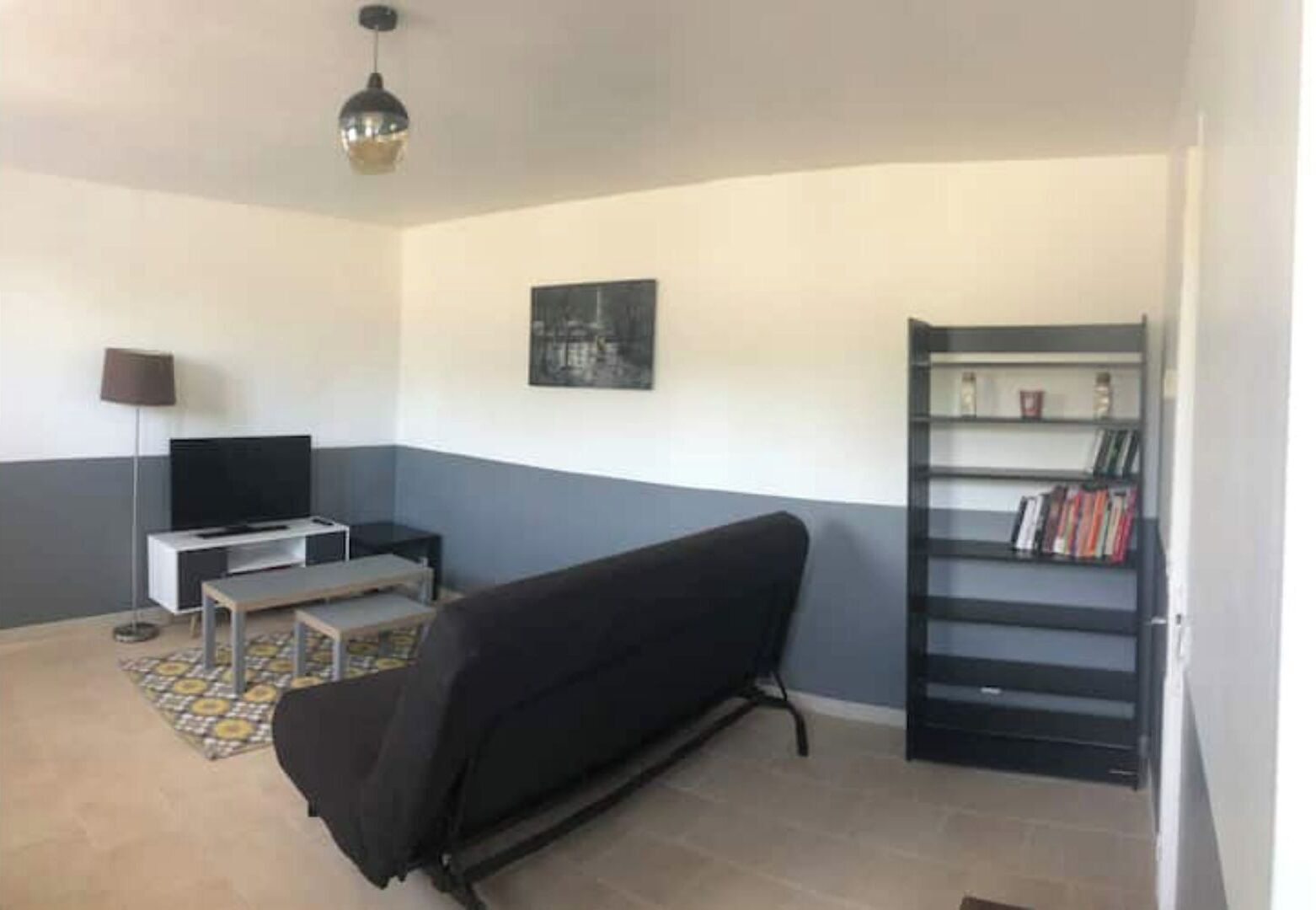 A living room with a sofa, a TV, a bookshelf, and a lamp.
