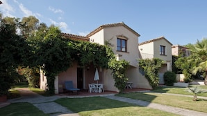 A two-story house with a patio area, a small table and chairs, and a bench. - Residence Baia Delle Palme (Pula)