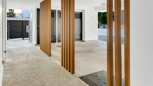A modern hallway with a concrete floor, wooden vertical panels, and a metal door with a parking sign. - Sanders Premier - Cozy 2 bdr apt With Balcony (Limassol)