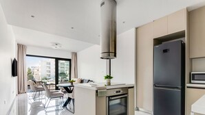 A modern kitchen with a built-in oven, a large refrigerator, and a dining area with a table and chairs. - Sanders Premier - Cozy 2 bdr apt With Balcony (Limassol)